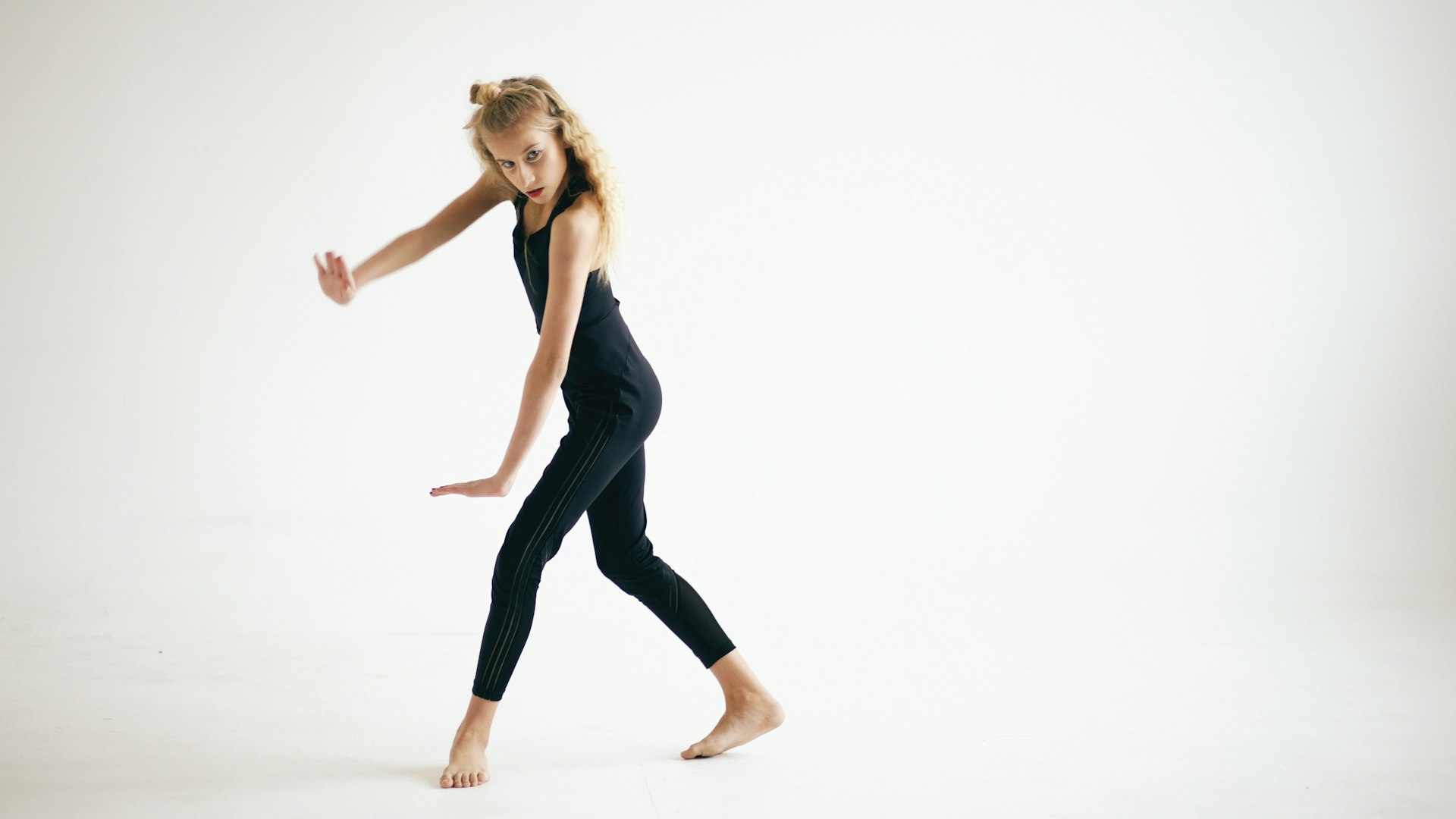 Young girl in black performing a dance move.